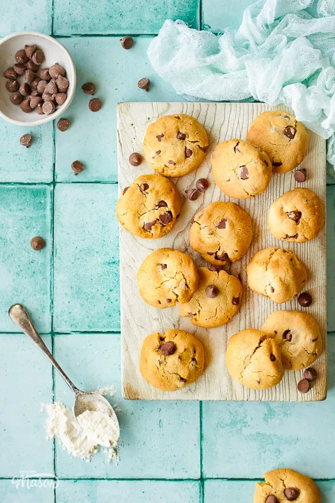 Air fryer cookies on a wooden board with chocolate chips scattered around