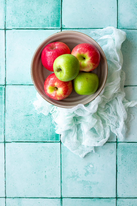 A bowl of apples on a light blue cloth