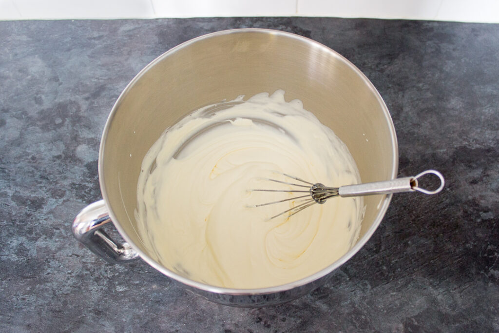 Whipped cream in a large bowl with a whisk