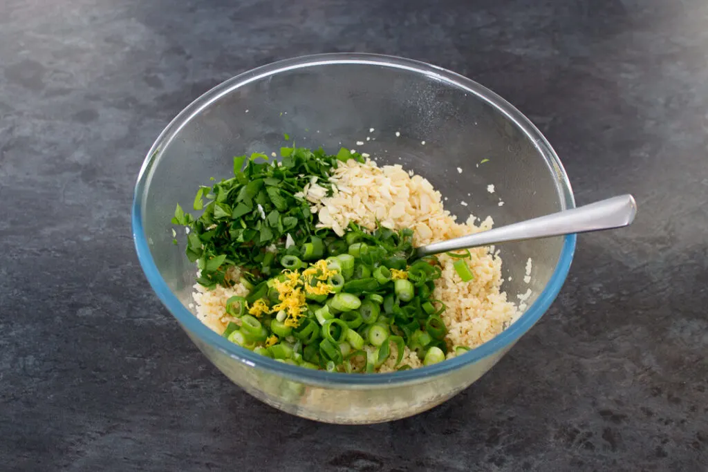 Couscous, spring onion and other ingredients, mixed together in a bowl