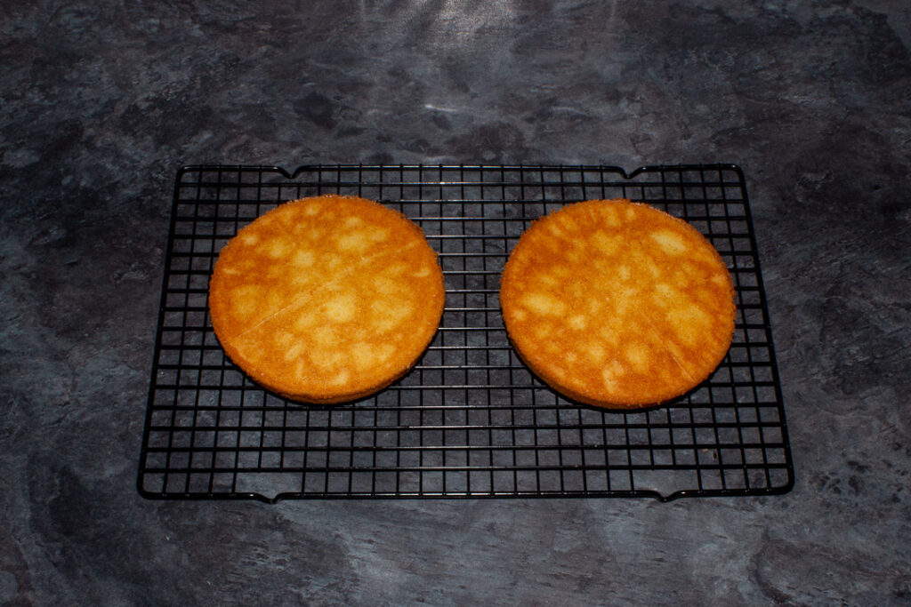 Two cakes cooling upside down on a rack