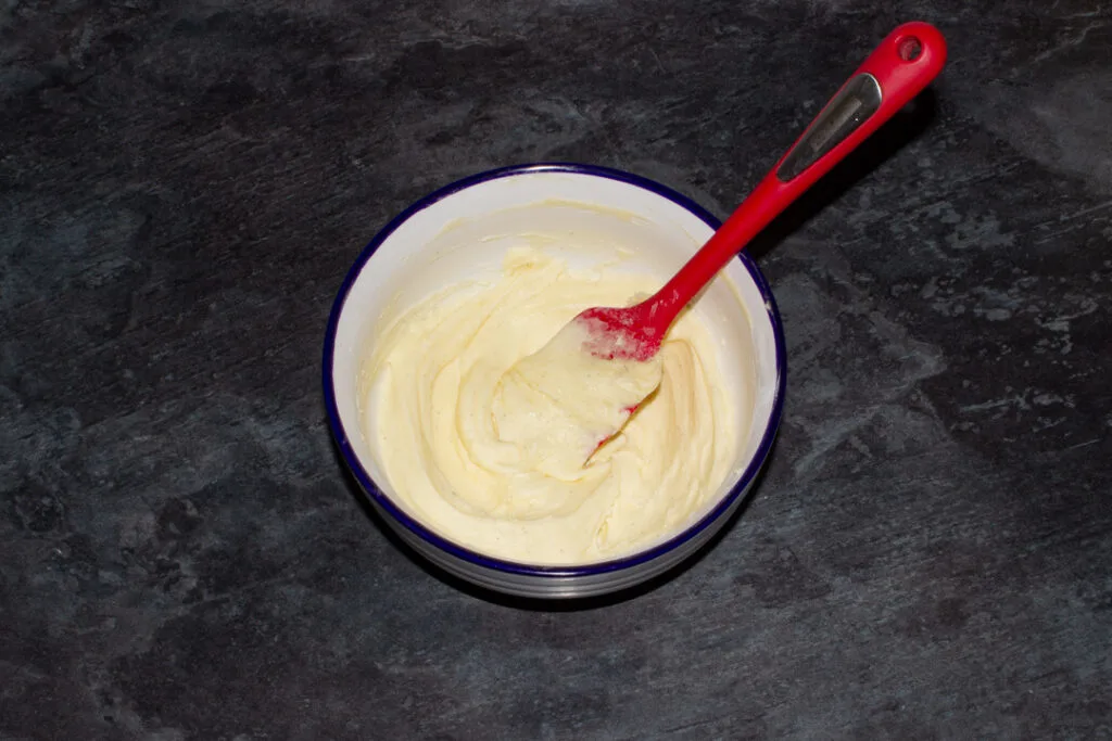 Smooth vanilla buttercream frosting in a bowl with a spatula