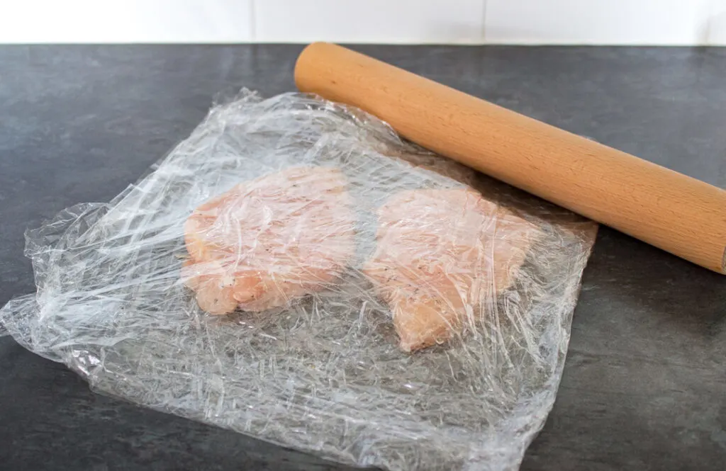 Chicken breasts being flattened with a rolling pin