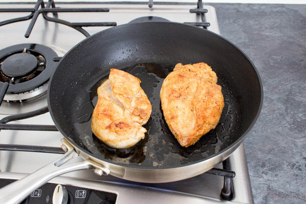 Crisp golden fried chicken breast in a frying pan