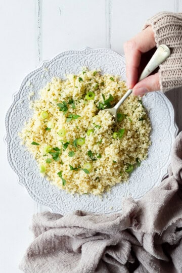 Someone forking couscous on a white plate