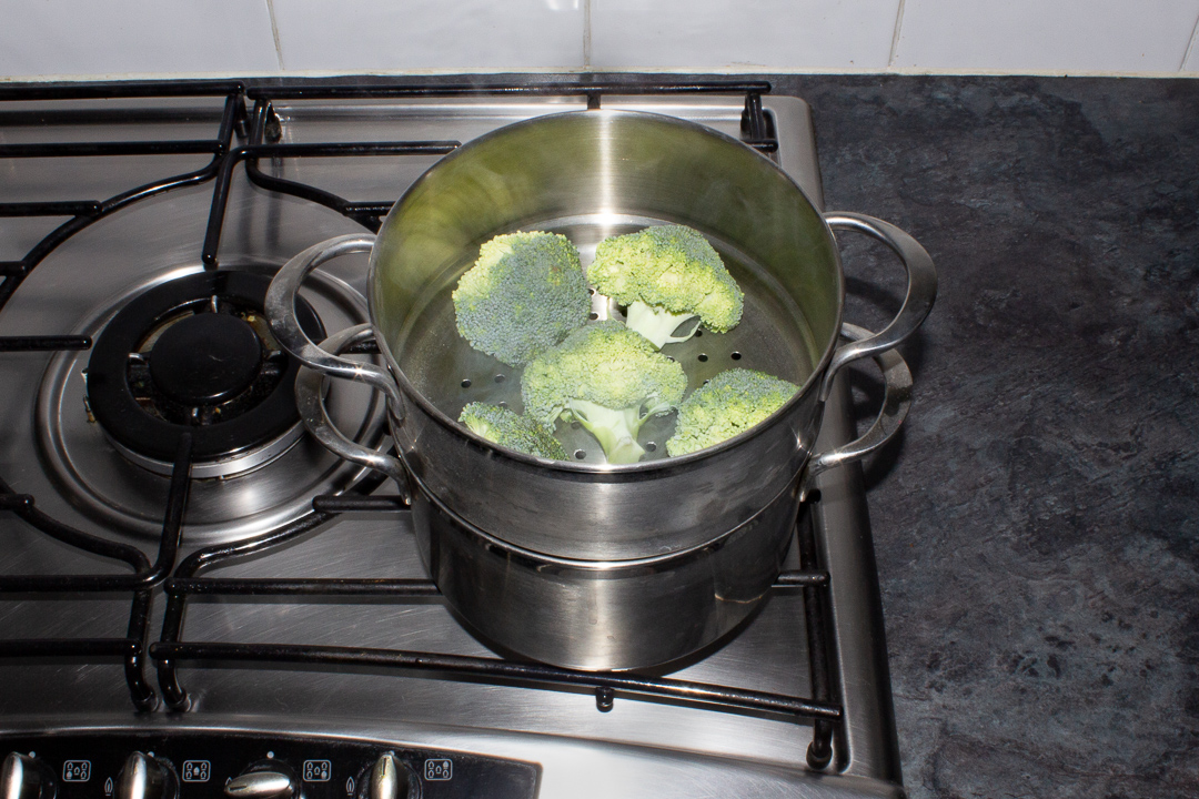 Broccoli steaming in a steamer on the stove