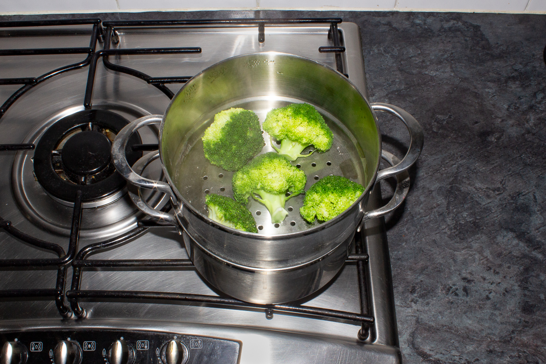 Steamed broccoli in a steamer on the hob