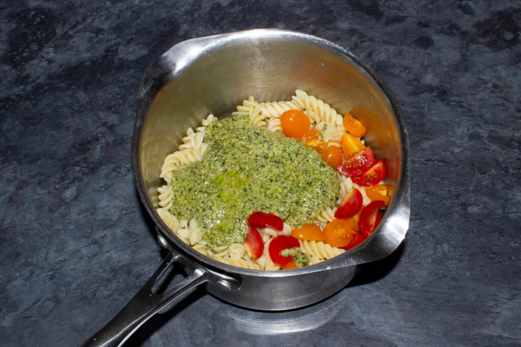 Cooked pasta, cherry tomatoes and pesto in a saucepan