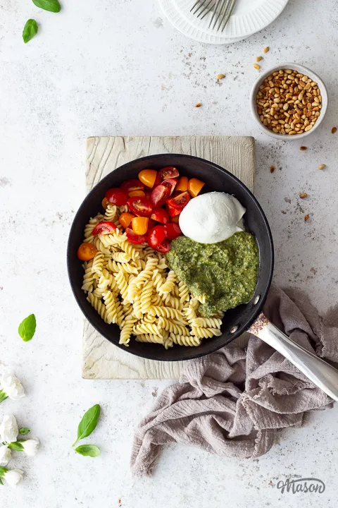 Cooked pasta, pesto, tomatoes and mozzarella in a frying pan