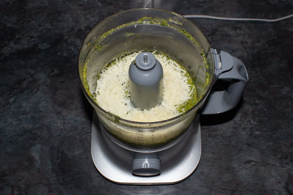 Liquidised pesto base ingredients in a food processor with grated parmesan