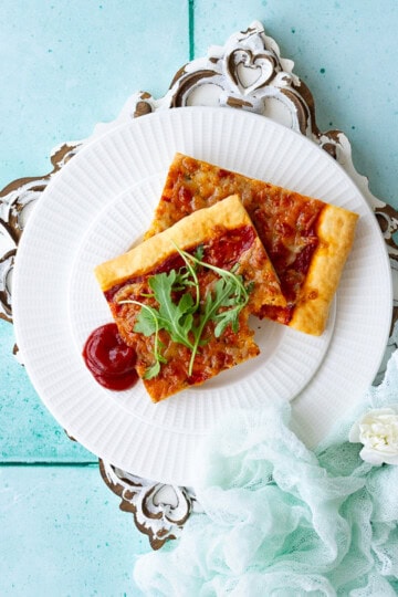 A plate of sliced pizza on a white patterned board