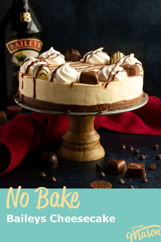 A whole no bake Baileys cheesecake on a cake stand with a bottle of Baileys behind it