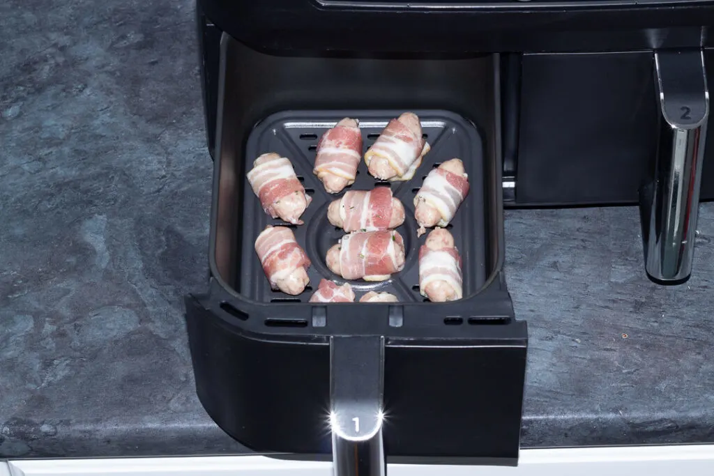 uncooked pigs in blankets in an air fryer drawer