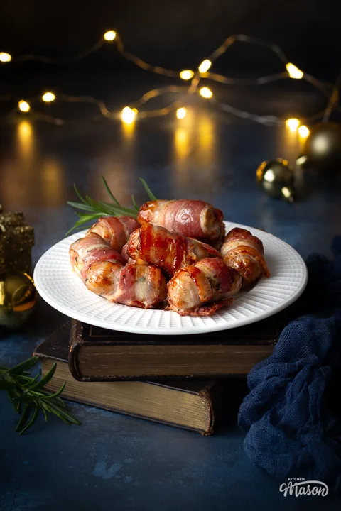 A plate of pigs in blankets on stacked books with Christmas lights