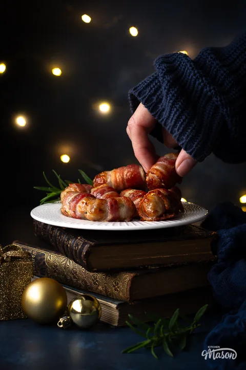 Someone taking pigs in blankets off a plate