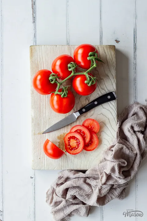 Tomatoes being sliced on a chopping board