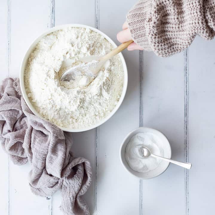 Someone stirring baking powder into plain flour