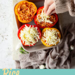 Someone topping rice stuffed peppers with grated mozzarella