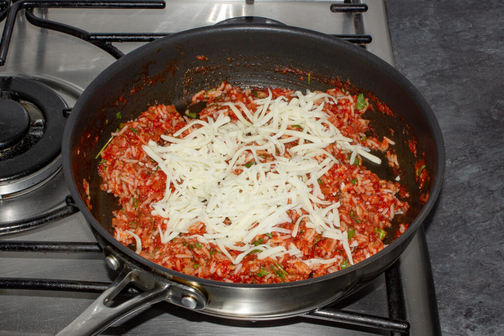 Rice stuffed peppers filling in a pan with grated mozzarella on top