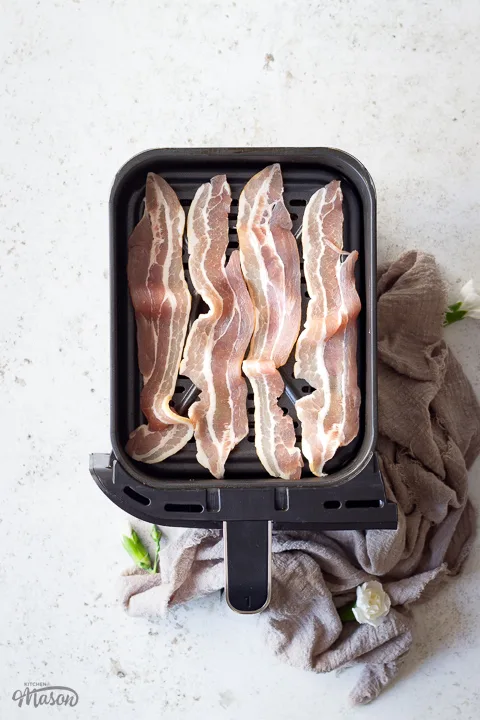 Uncooked streaky bacon in an air fryer drawer