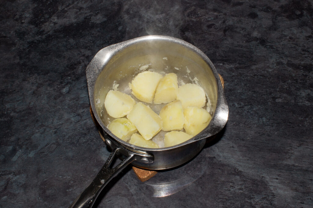 par boiled potatoes fluffed up in a pan