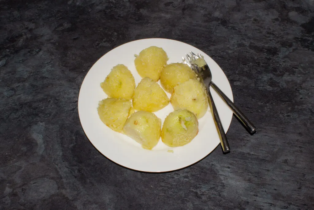 Part cooked potatoes being fluffed up with a fork