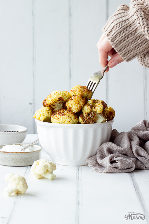 Someone forking a floret of roast cauliflower from a bowl