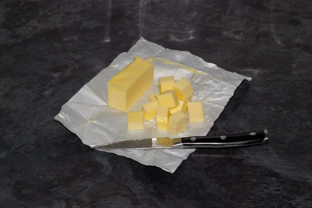 A block of butter being cubed with a sharp knife