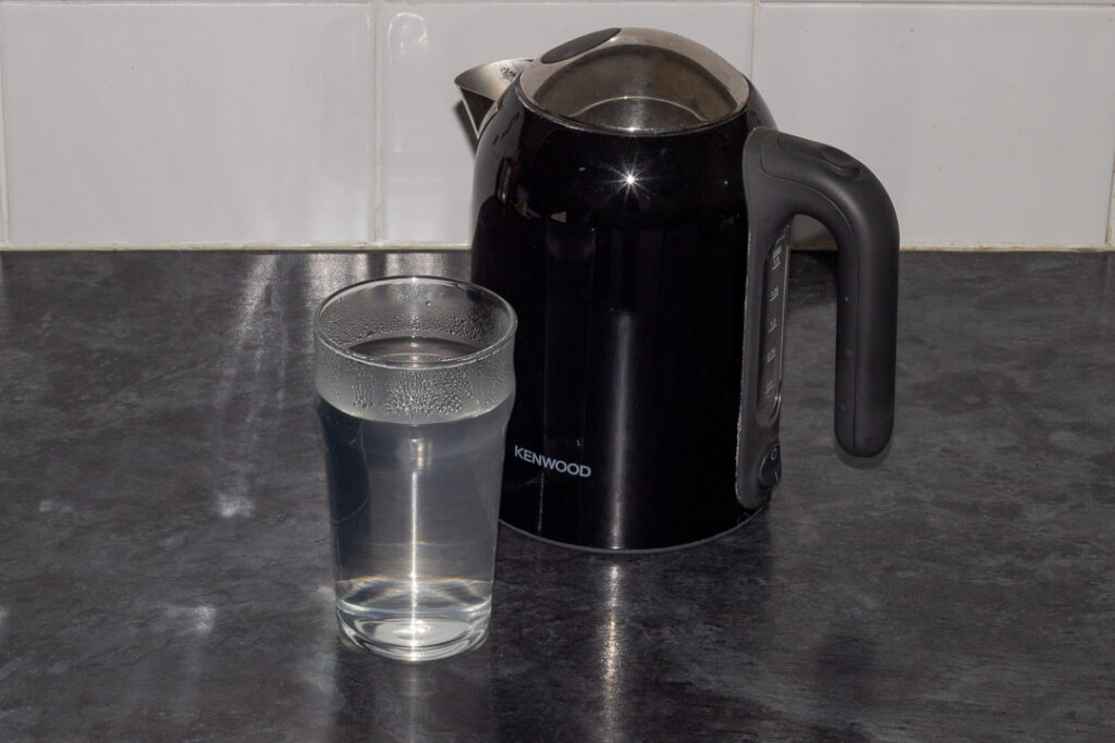 A glass of hot water and a kettle