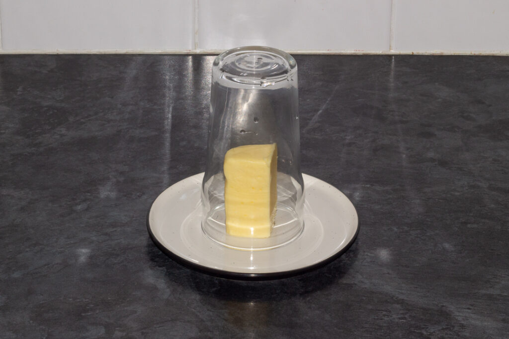 A warm glass over a stick of butter on a plate