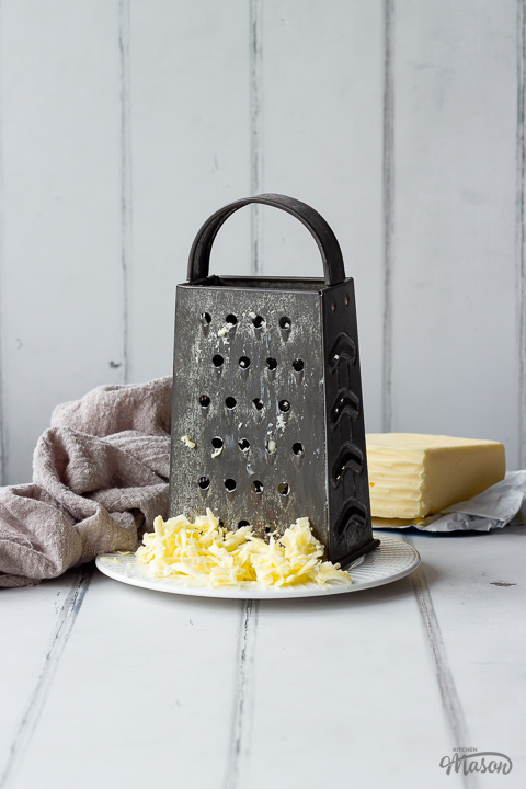A box grater and grated butter on a plate