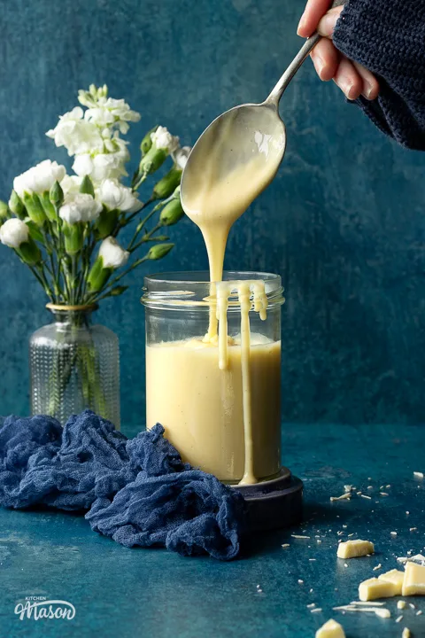 Someone dripping white chocolate sauce into a jar