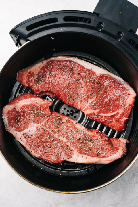 Uncooked pork chops in an air fryer drawer