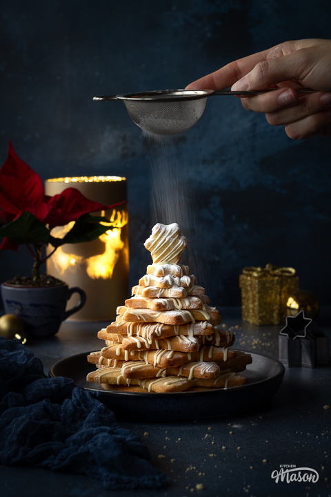 Someone dusting a christmas cookie tree with icing sugar