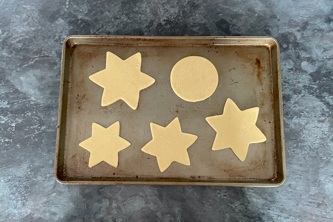 Unbaked cookie shapes on a large baking tray