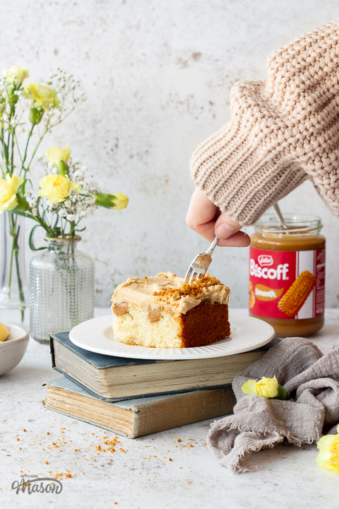 Someone forking a slice of Biscoff traybake cake on a plate