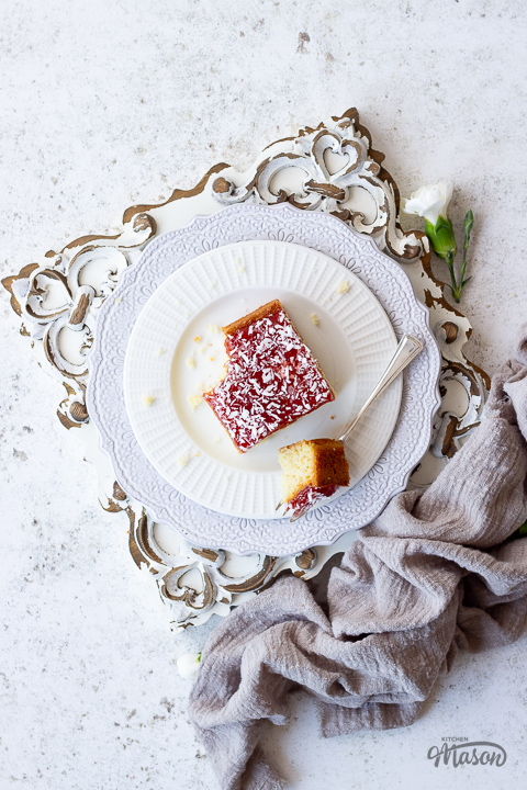 A slice of coconut jam cake on a plate with a fork.