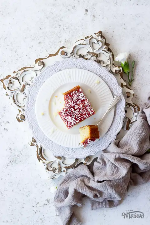 A slice of coconut jam cake on a plate with a fork.