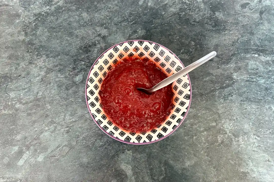 Jam in a small bowl with a spoon