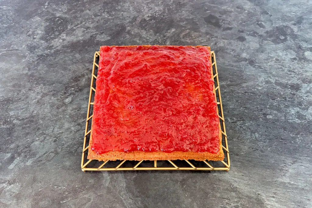 Jam spread on top of a vanilla sponge cake.