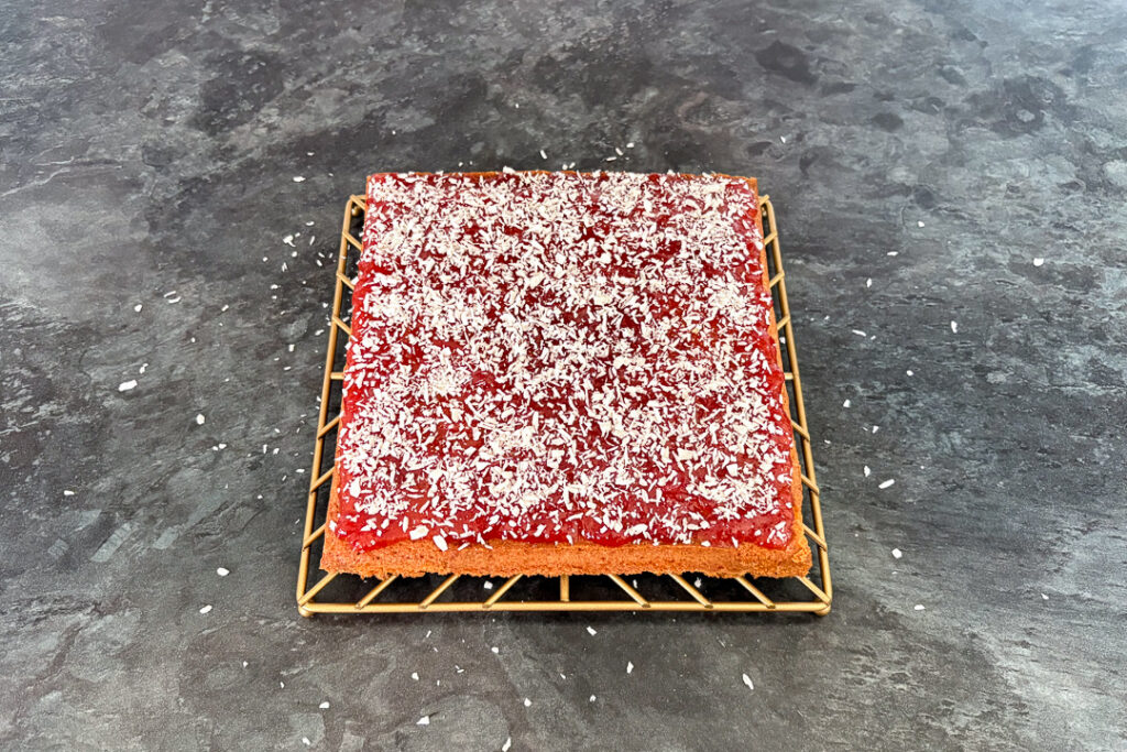 Coconut sprinkled over a cake topped with jam.