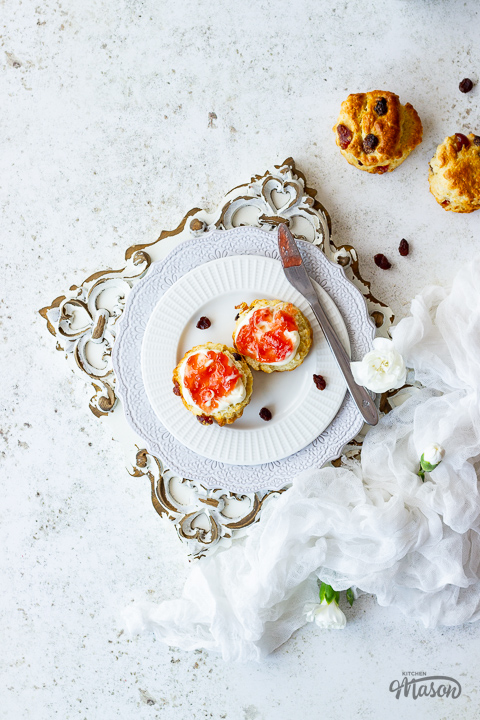 Fruit scones with jam and cream on a plate with a knife