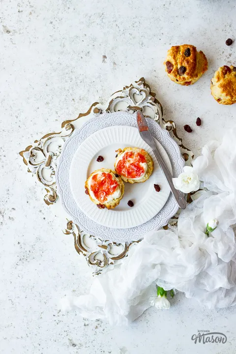 Fruit scones with jam and cream on a plate with a knife