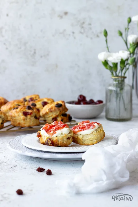 A split fruit scone topped with jam and clotted cream