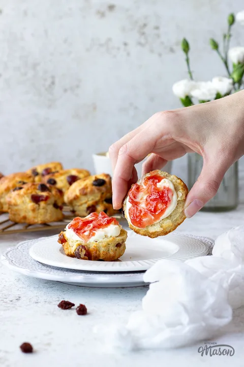 Someone picking up a fruit scone