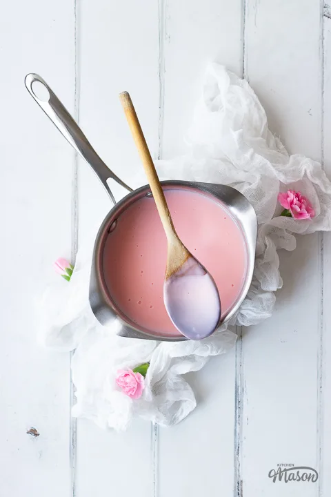 Pink custard in a saucepan with a spoon resting over it