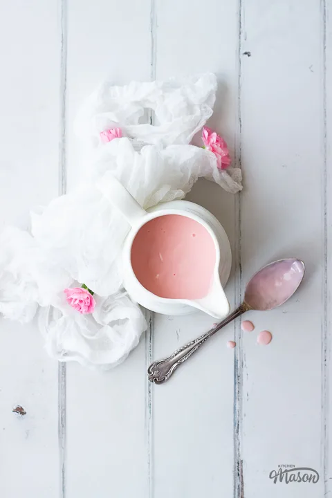 Pink custard in a jug on a white napkin