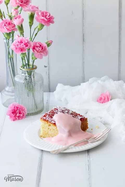A plate with coconut jam cake and pink custard on it