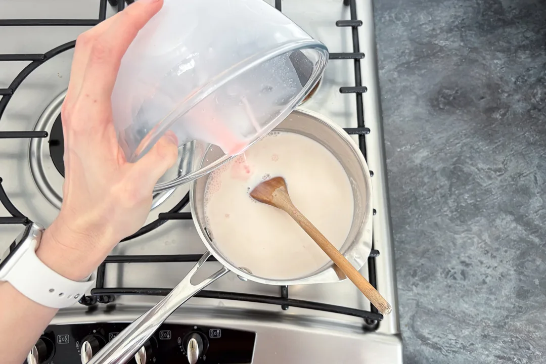 Blancmange paste being poured into hot milk in a saucepan