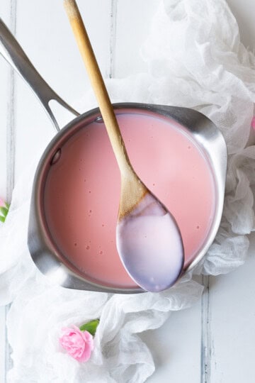 pink custard in a saucepan with a spoon